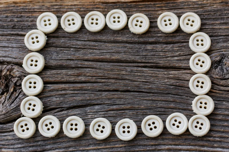 Cream buttons arranged in a rectangular frame on a weathered wooden surface