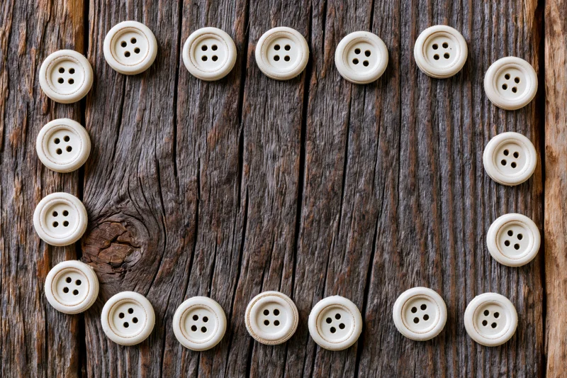Cream buttons arranged in a circular frame on a weathered wooden surface