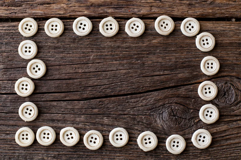 Cream-colored sewing buttons arranged in a circular frame on a rustic wooden surface