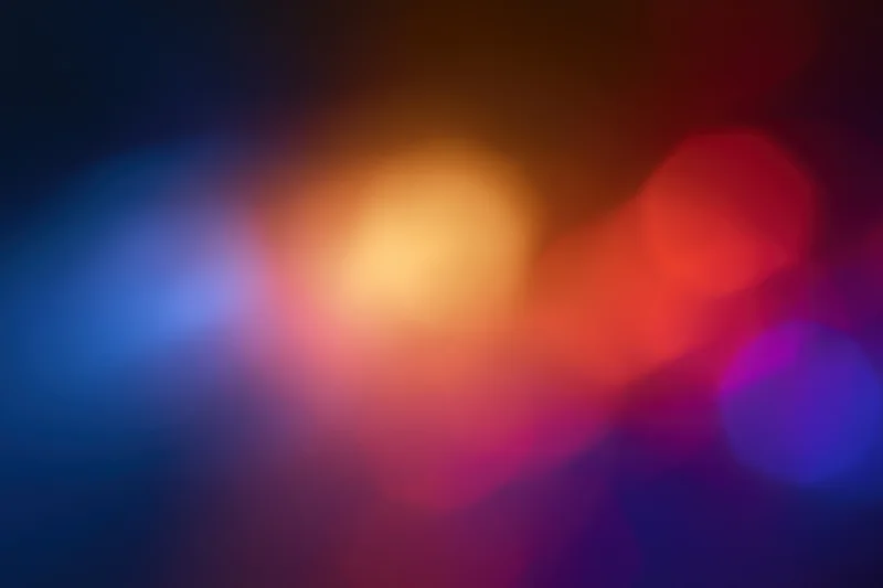 Blurred bokeh lights in red blue and orange hues against dark background
