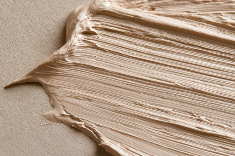 Thick creamy beige cosmetic cream smeared across a flat surface