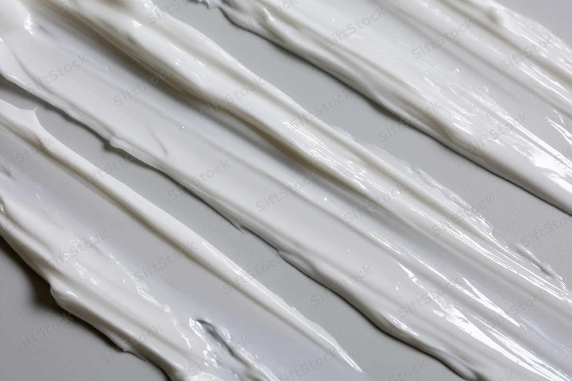 Diagonal swipes of white cream smeared across a smooth surface