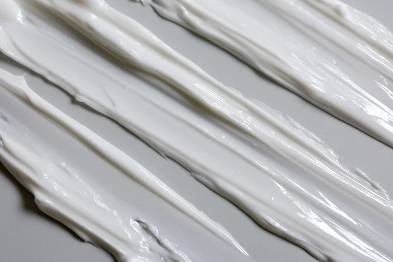 Diagonal swipes of white cream smeared across a smooth surface