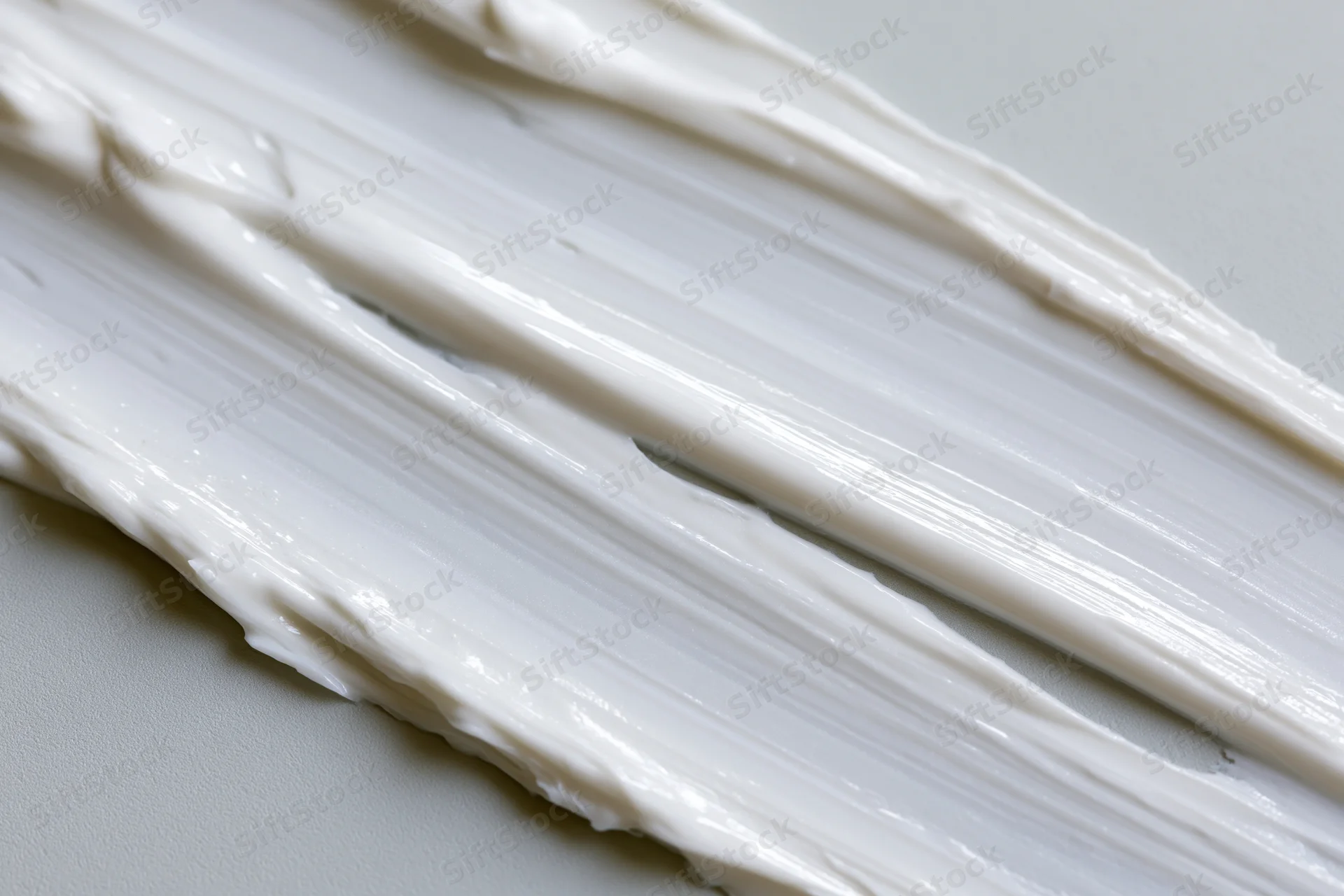 Diagonal swipes of white cream smeared across a smooth surface