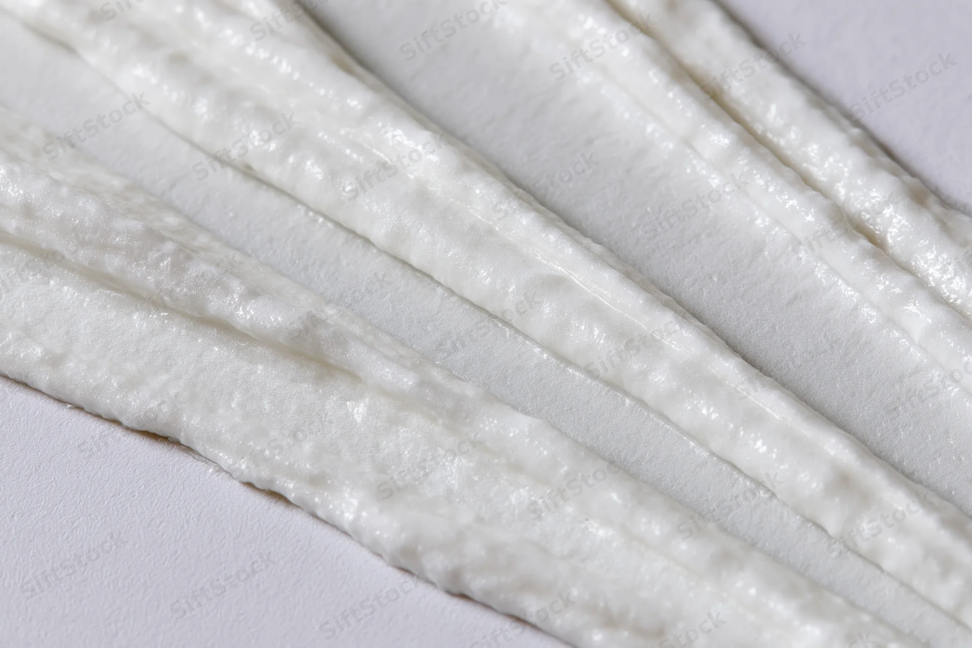 Diagonal swipes of white cream smeared across a surface