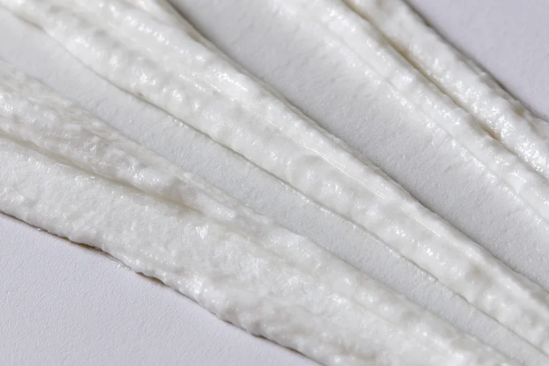 Diagonal swipes of white cream smeared across a surface
