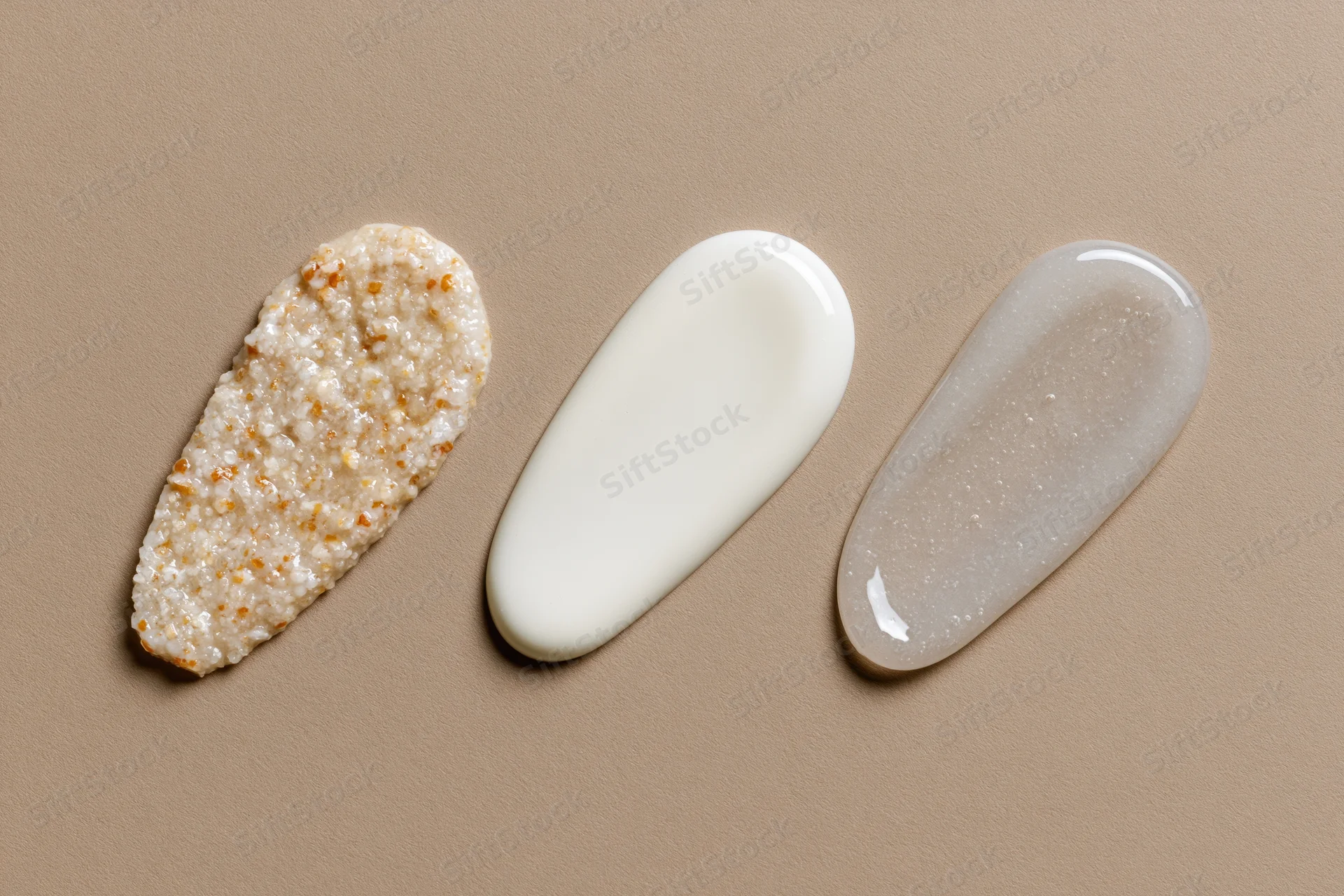 Three skincare product smears arranged in a row on a matte tan surface