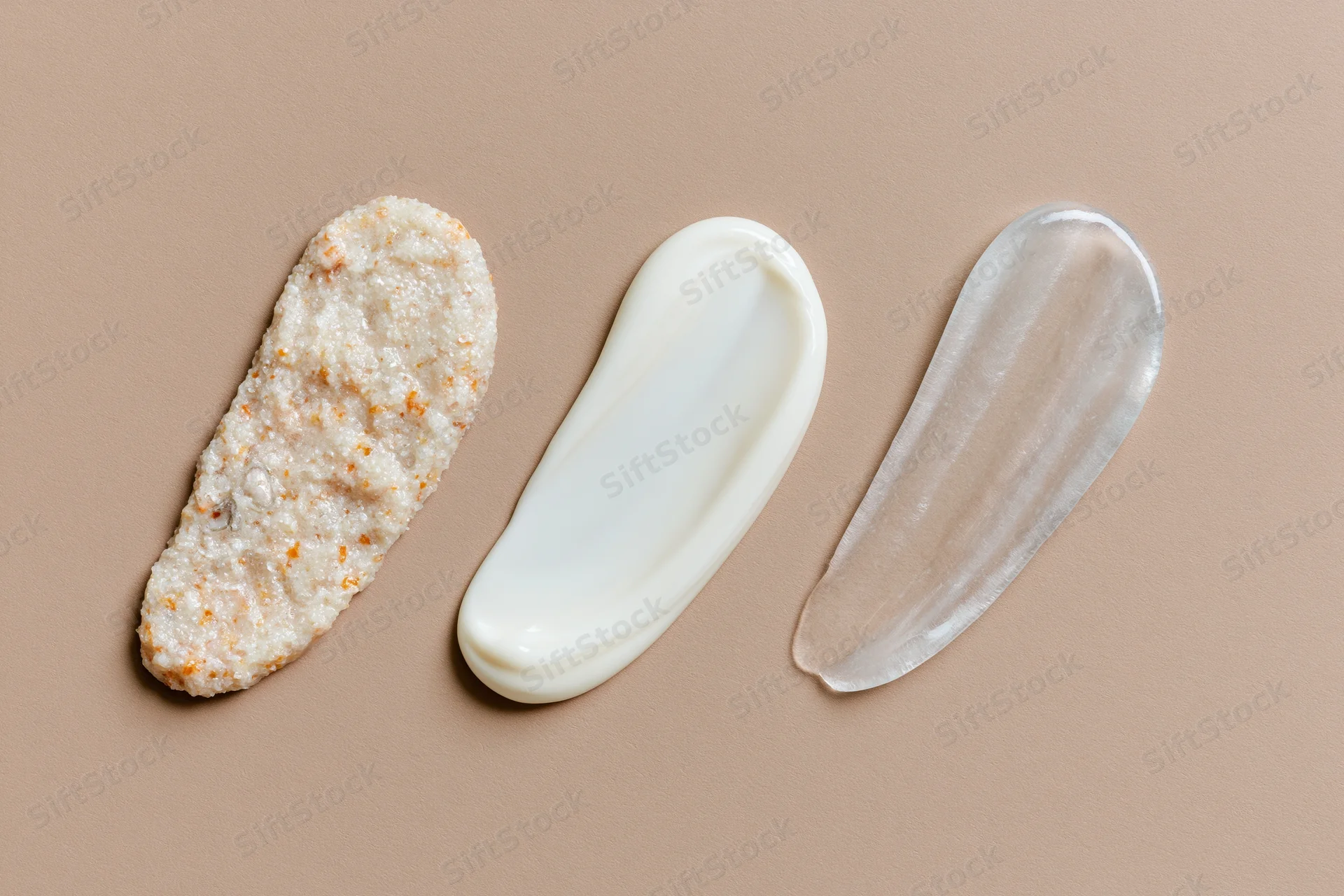 Three skincare product smears arranged in a row on a matte beige surface