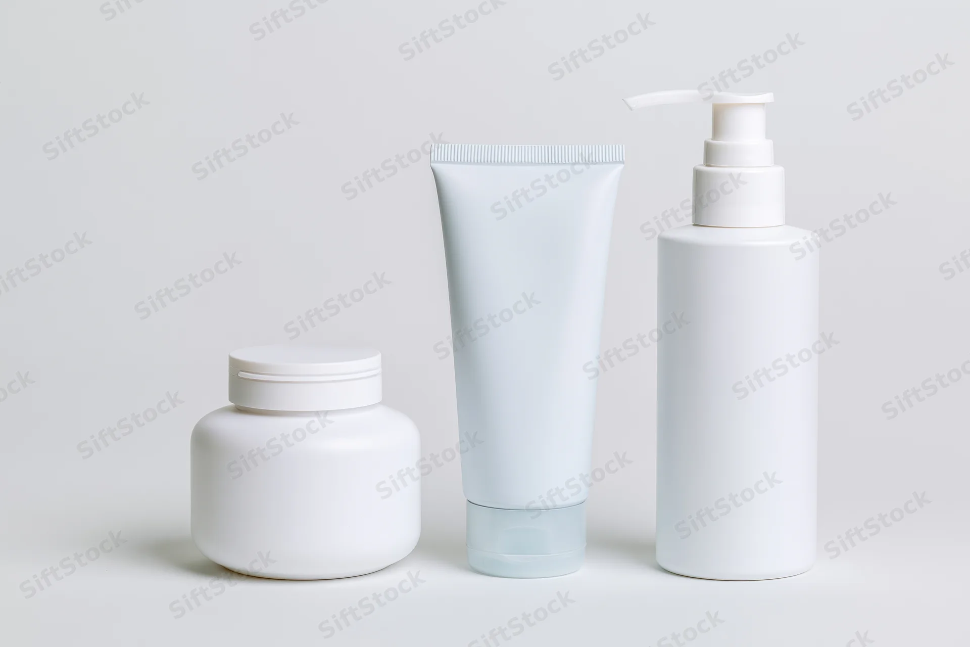 Three white unlabeled skincare containers arranged in a row on a plain white surface