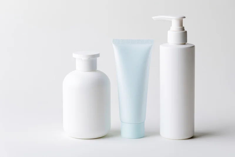 Three unlabeled white skincare containers arranged in a row on a plain white surface