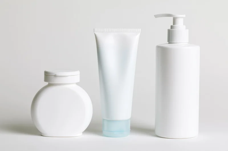 Three white unlabeled skincare containers arranged in a row on a plain surface