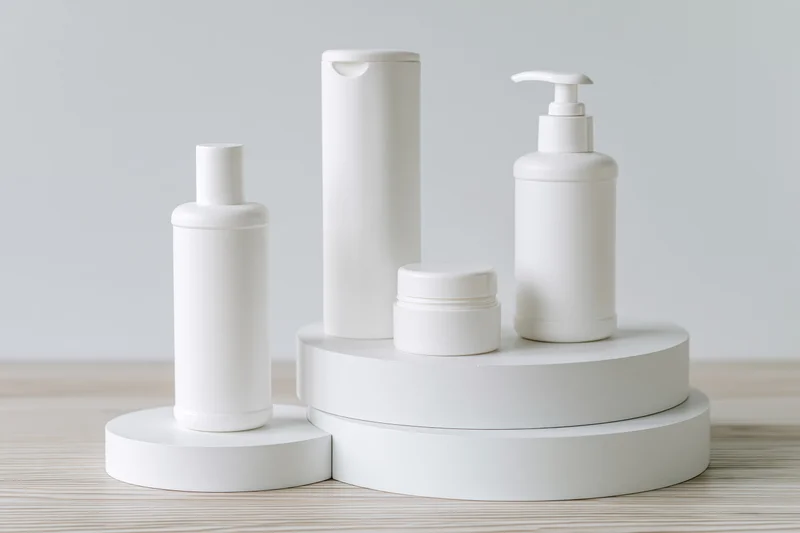 White skincare product containers arranged on tiered stands on wooden surface