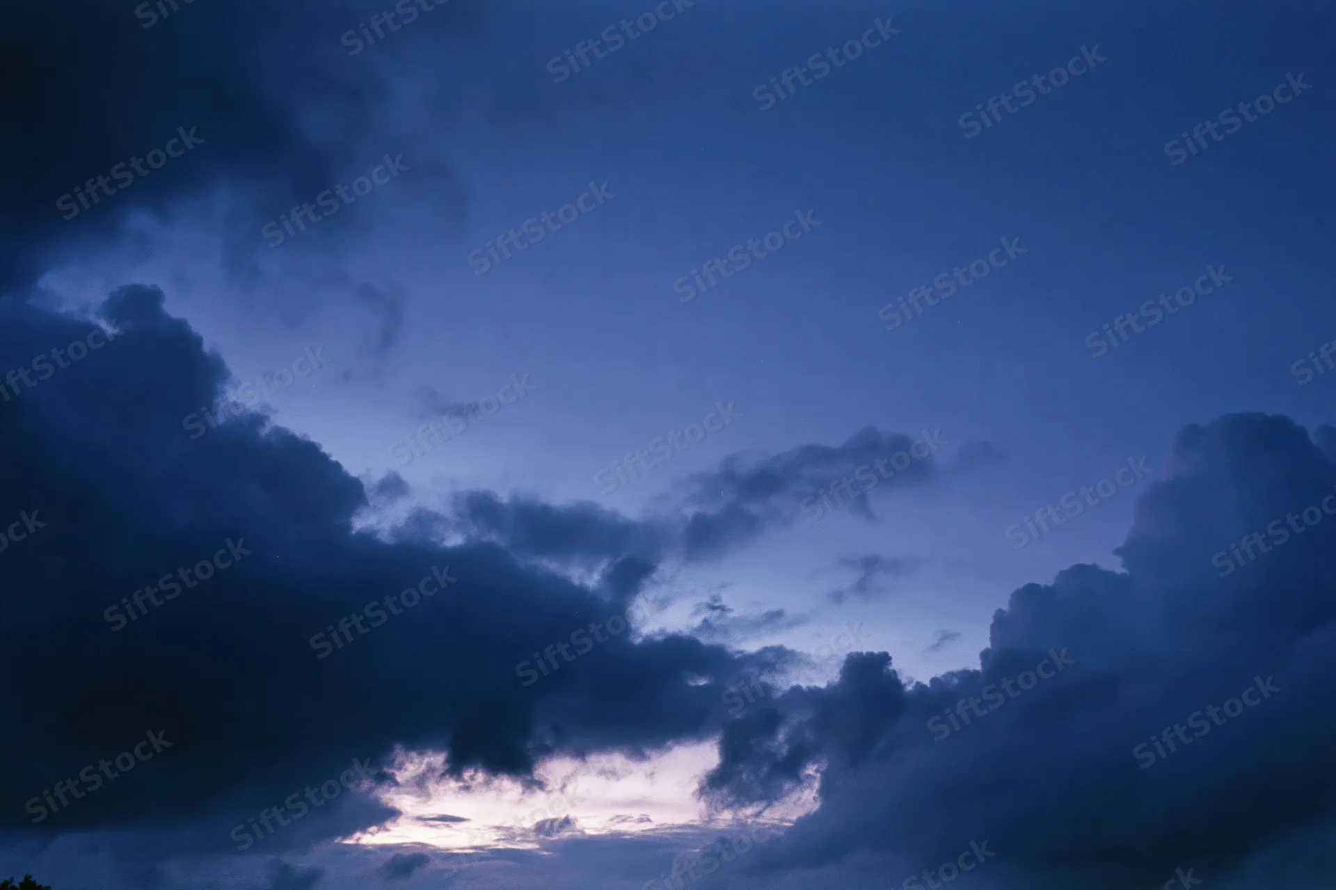 Twilight sky with scattered dark storm clouds at dusk