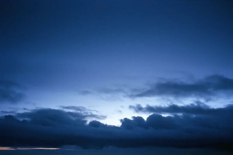 Twilight sky with scattered dark clouds at dusk over the horizon