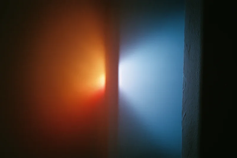 Contrasting orange and blue light beams meeting in a dark interior space