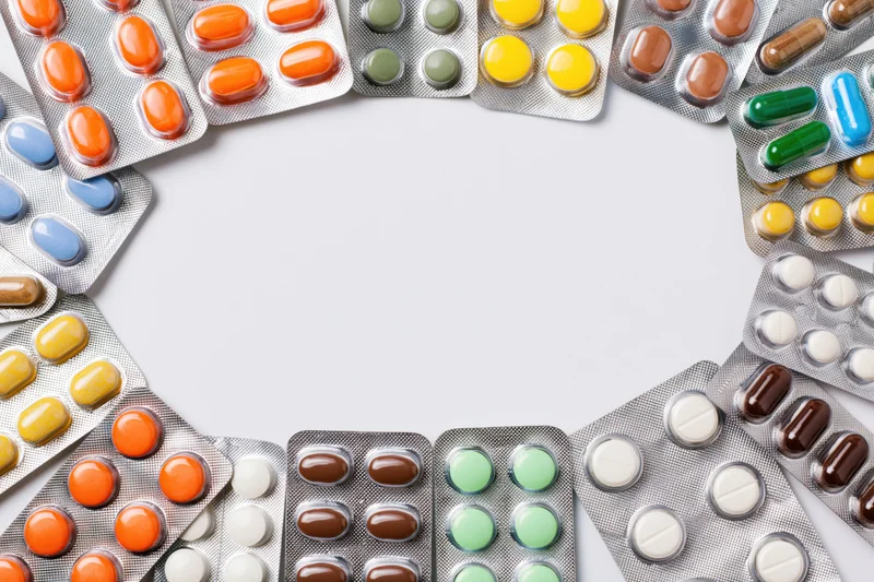 Various pharmaceutical blister packs arranged in a border frame on white background with copyspace