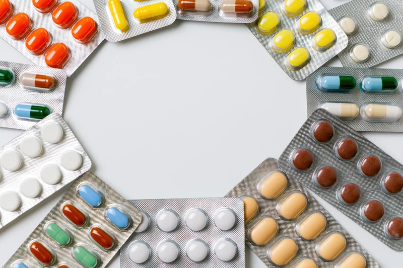 Various pharmaceutical blister packs arranged in a border frame on white background with copyspace