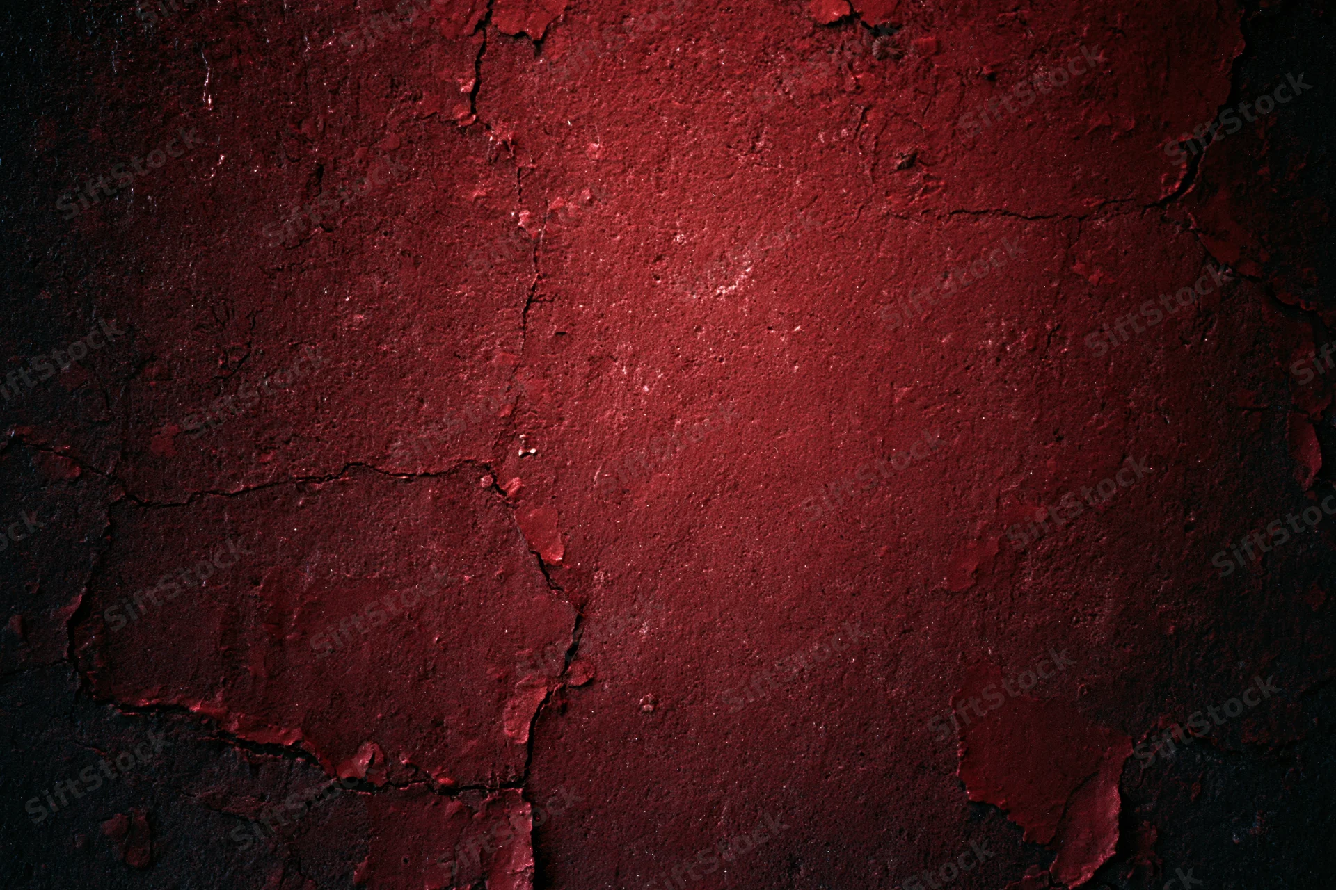 Weathered concrete wall with peeling red paint and cracks
