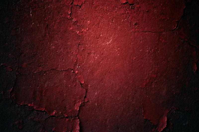 Weathered concrete wall with peeling red paint and cracks