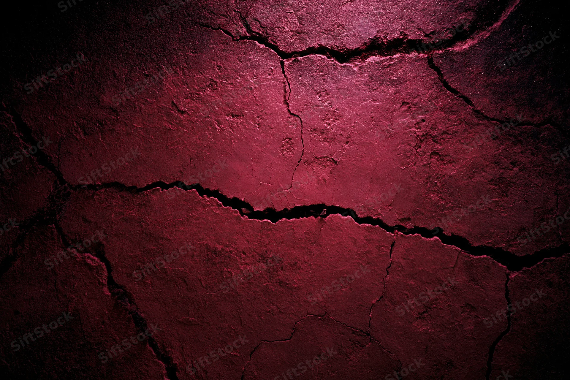 Cracked red concrete wall surface with peeling paint and deep fissures