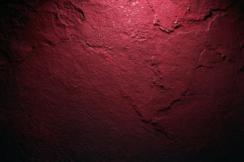 Weathered red concrete wall with cracked and peeling paint texture