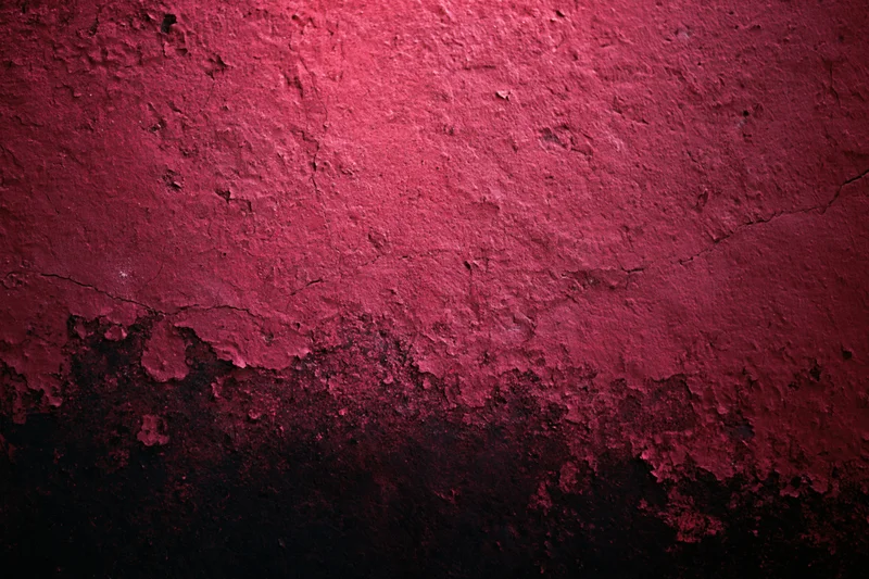 Weathered red concrete wall with peeling paint and cracks