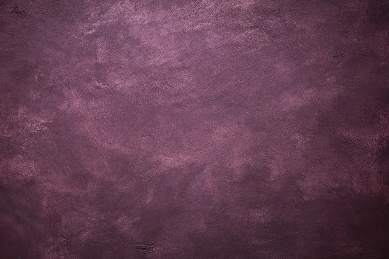 Weathered plaster wall surface filling the frame with textured purple and gray tones