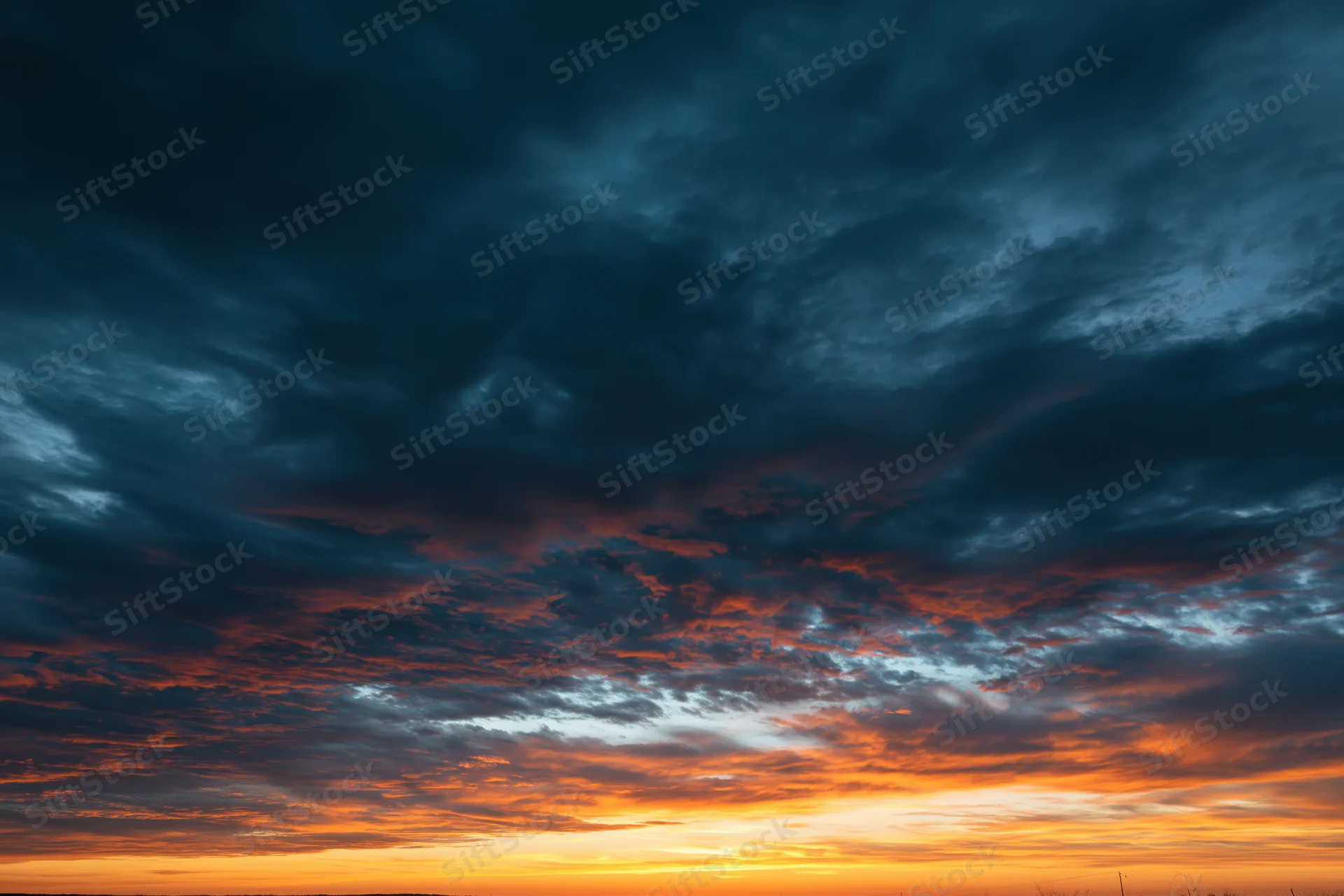 Dramatic layered clouds at sunset filling the sky with orange and blue hues