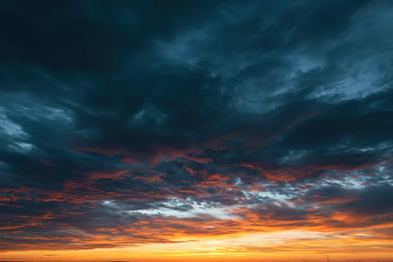 Dramatic layered clouds at sunset filling the sky with orange and blue hues