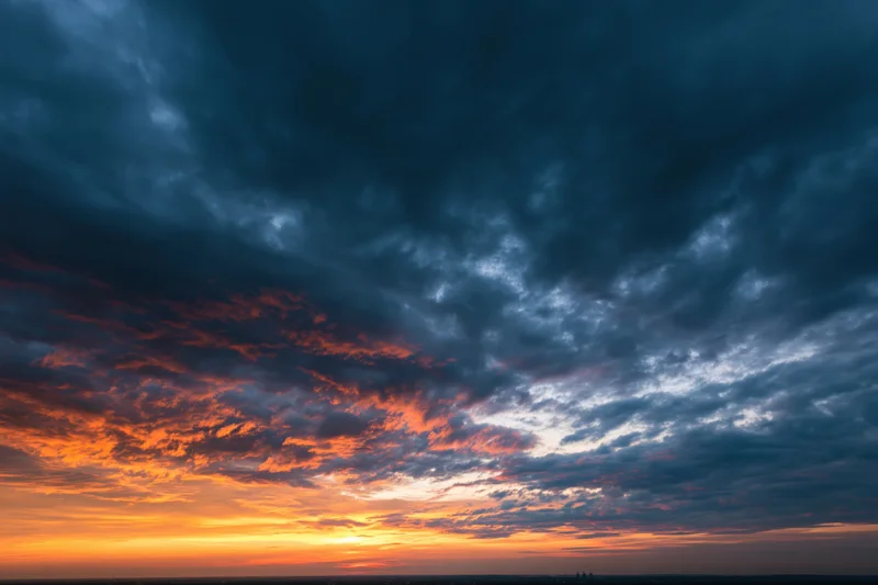 Dramatic sky at sunset with layered clouds and fiery orange glow near horizon