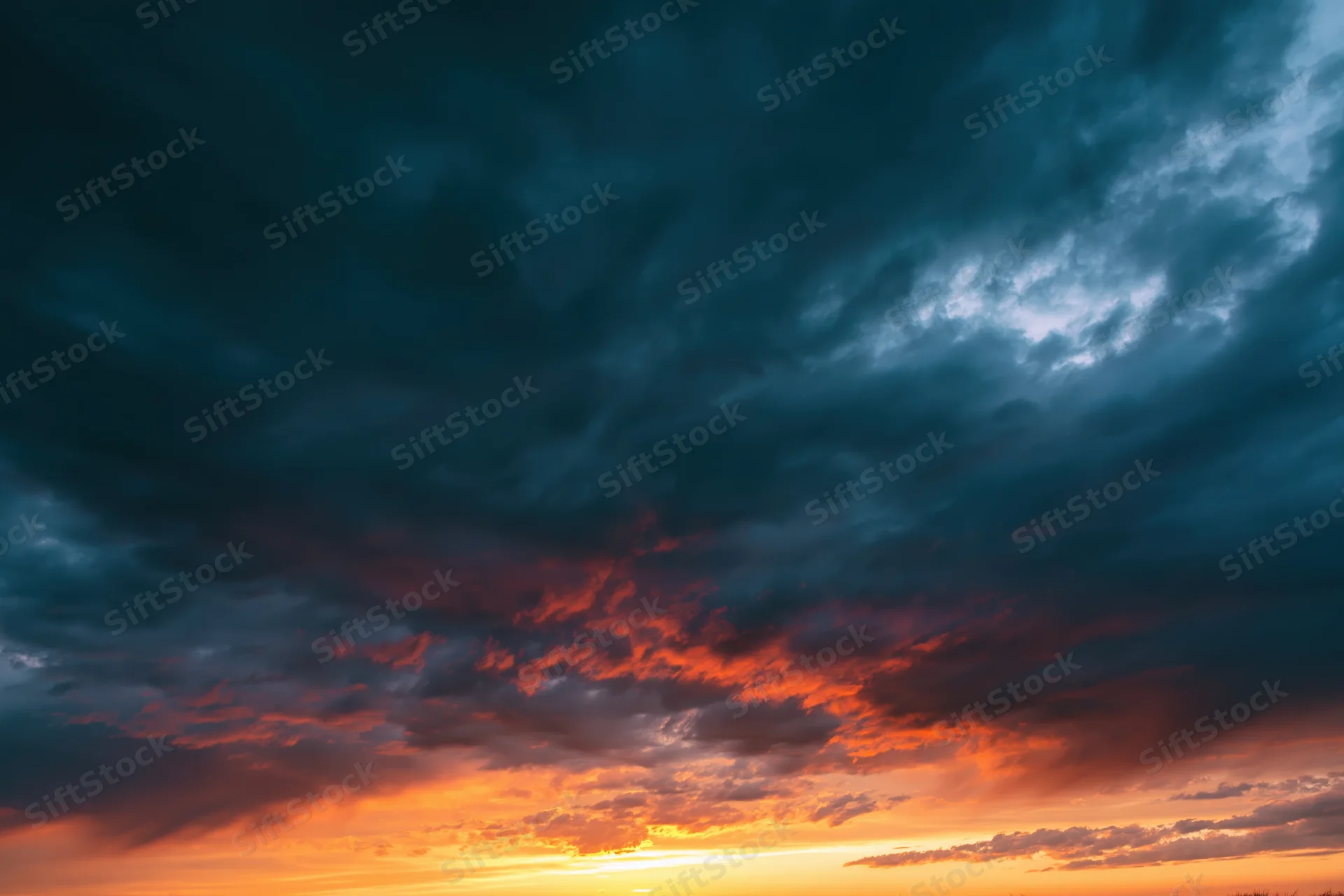 Dramatic sky at sunset with layered clouds and vibrant orange and blue hues