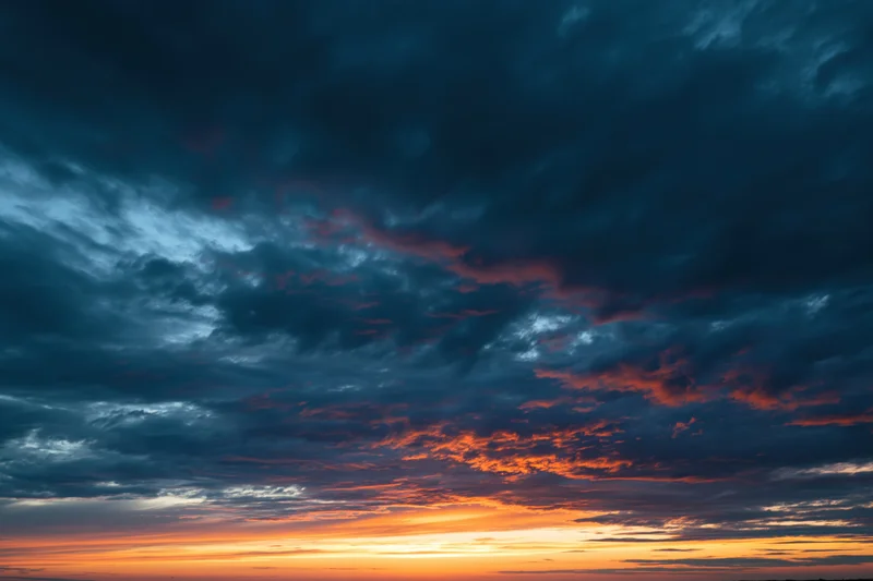 Dramatic sky at sunset with layered clouds and orange blue gradient across the horizon