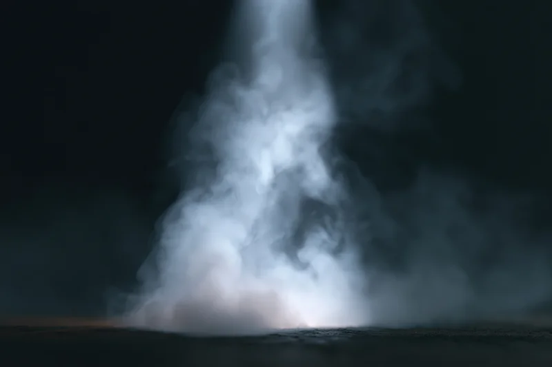 White smoke rising from a dark surface in a studio setting