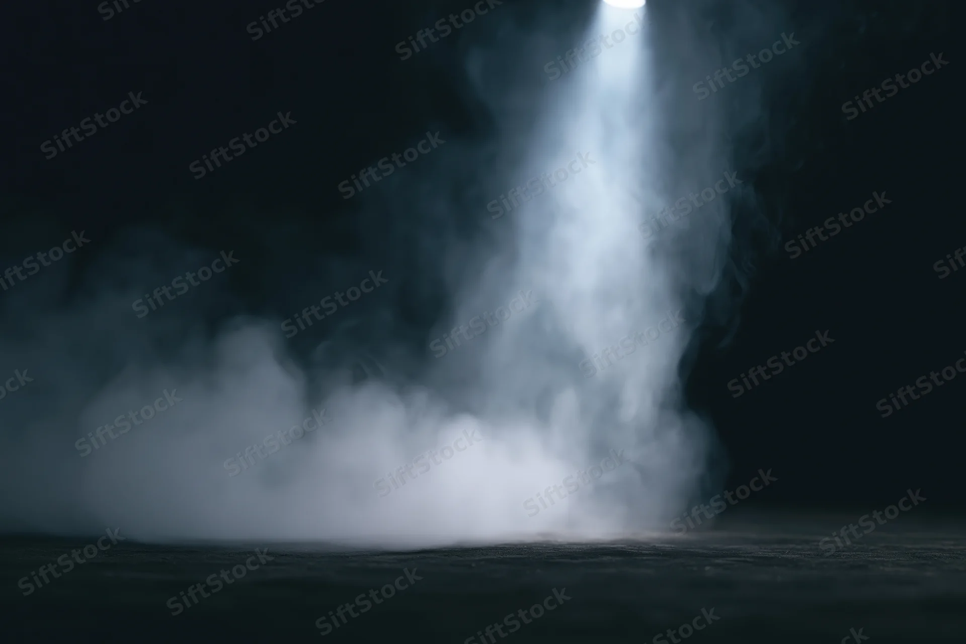 White smoke rising in a spotlight on a dark studio floor