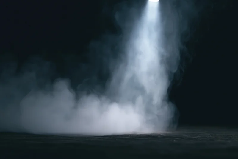 White smoke rising in a spotlight on a dark studio floor