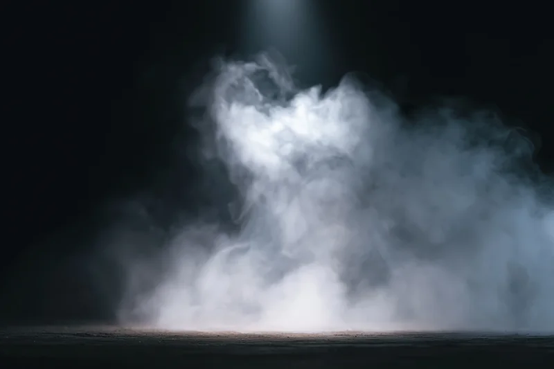 White smoke rising in a dark studio under a spotlight