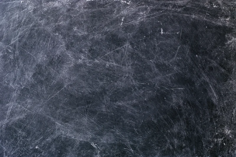 Worn black chalkboard surface covered in chalk dust and fine scratches