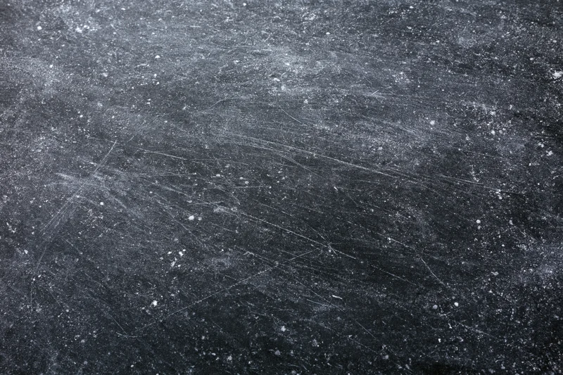 Worn black chalkboard surface covered in chalk dust and fine scratches