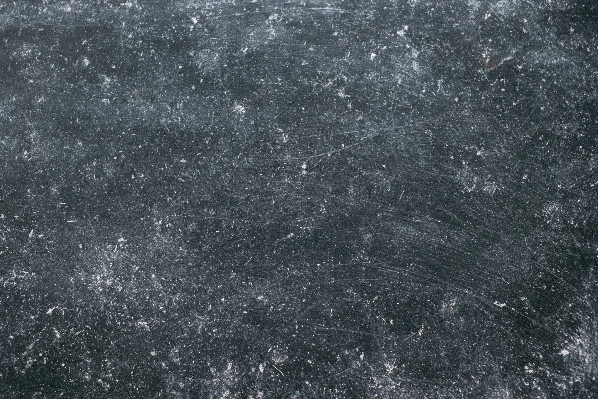 Worn black chalkboard surface covered in chalk dust and scratches