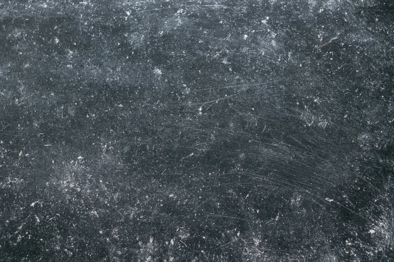 Worn black chalkboard surface covered in chalk dust and scratches