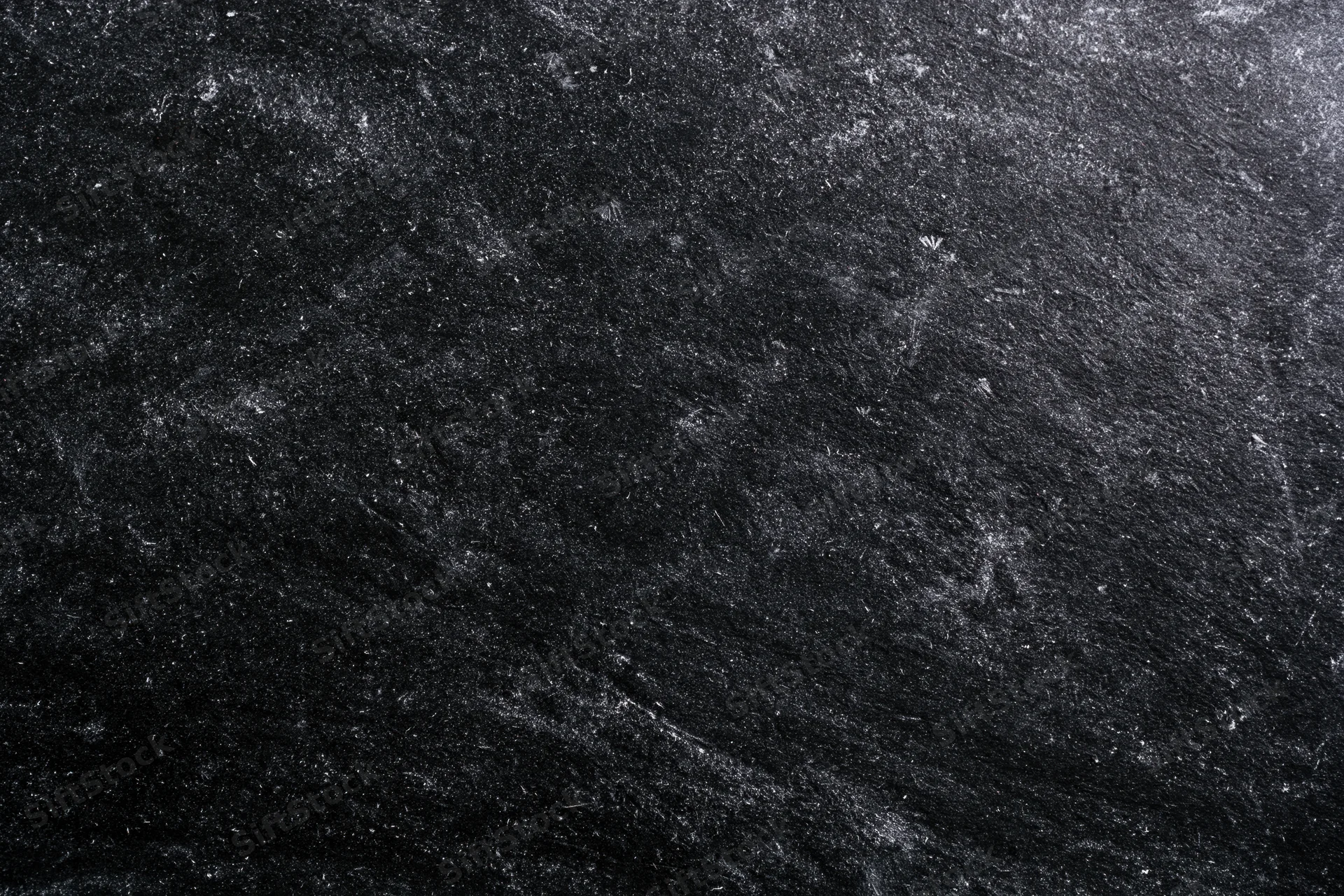Worn black chalkboard surface with chalk dust and scratches