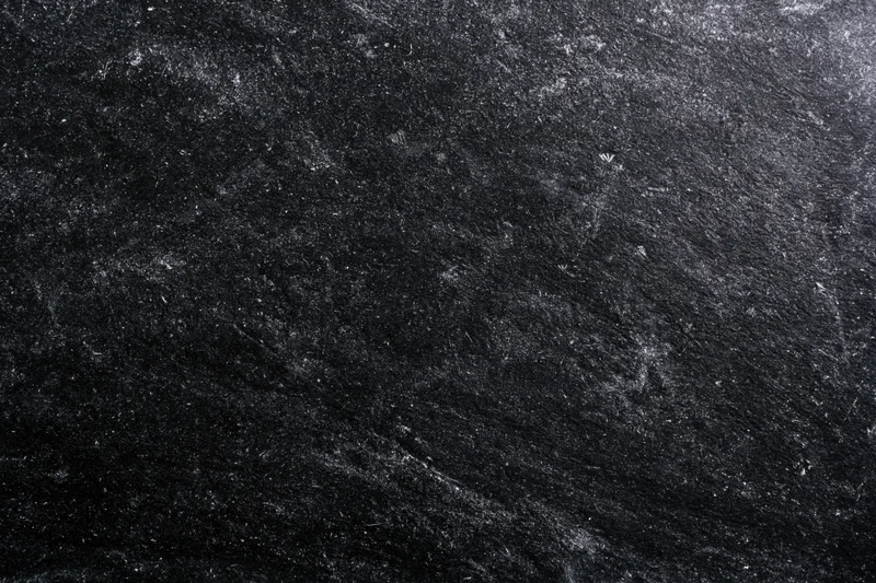 Worn black chalkboard surface with chalk dust and scratches