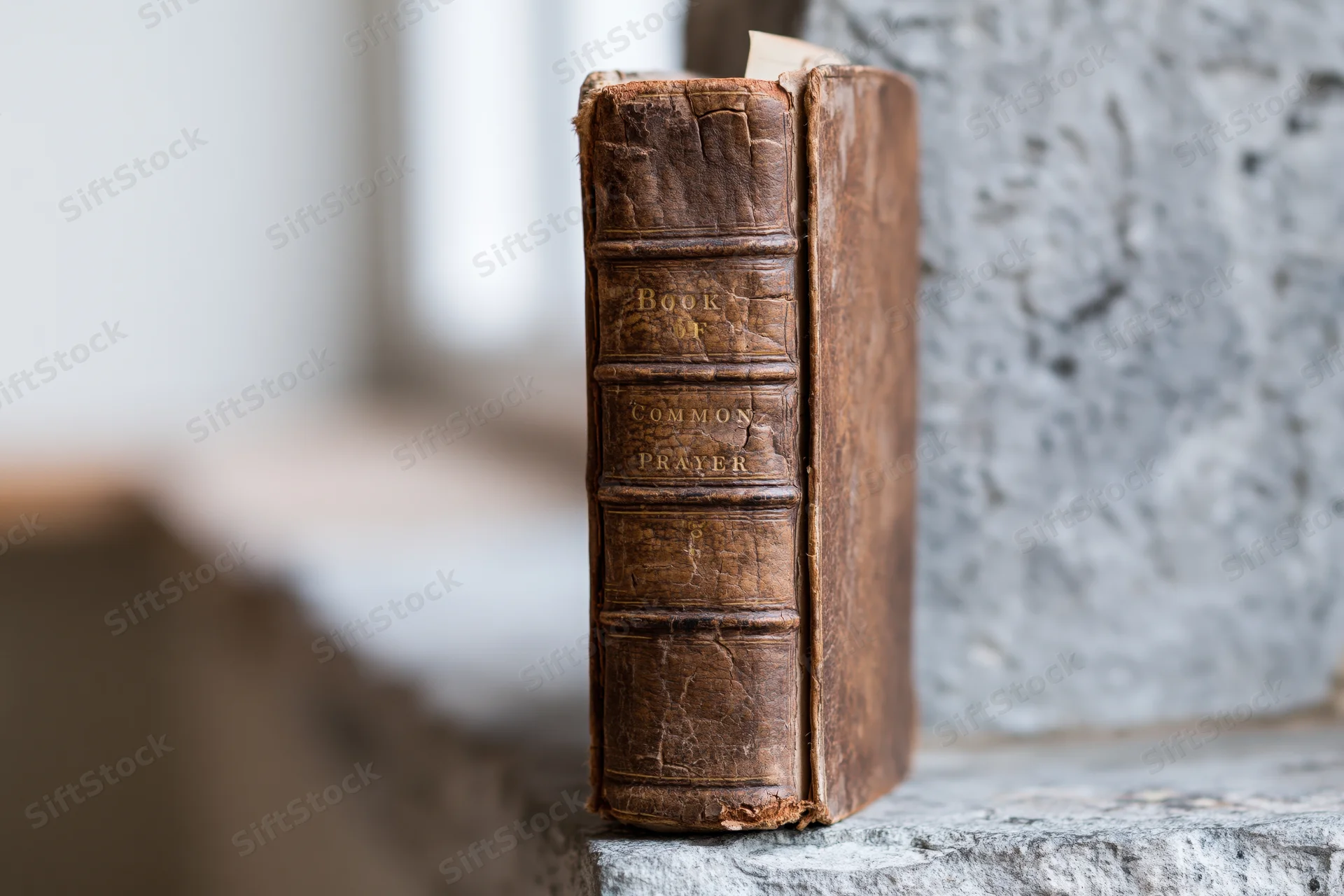 Worn leather-bound book of common prayer standing upright on stone surface outdoors