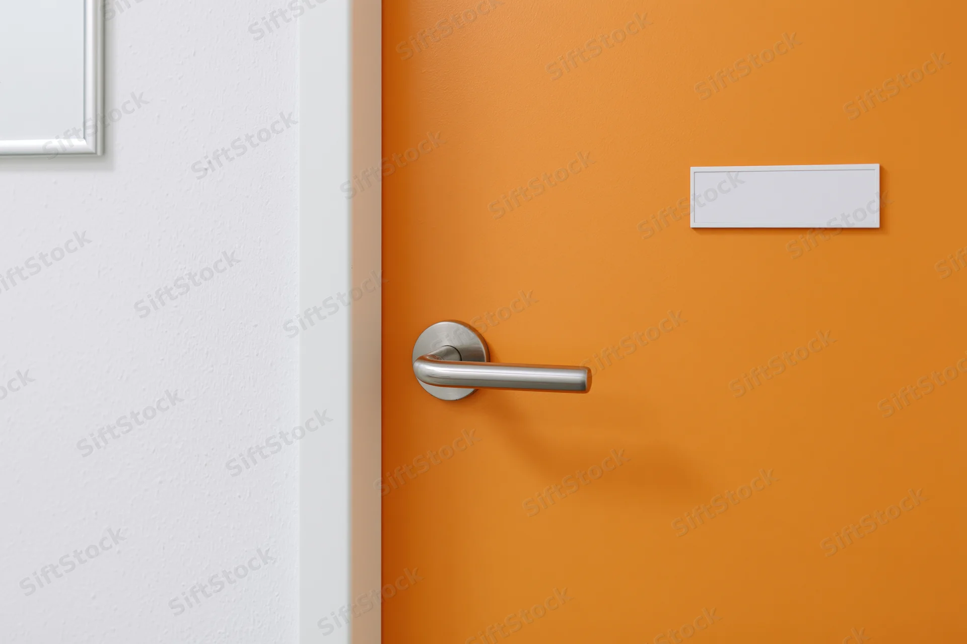 Bright orange interior door with brushed silver lever handle and blank white label plate, adjacent to white wall