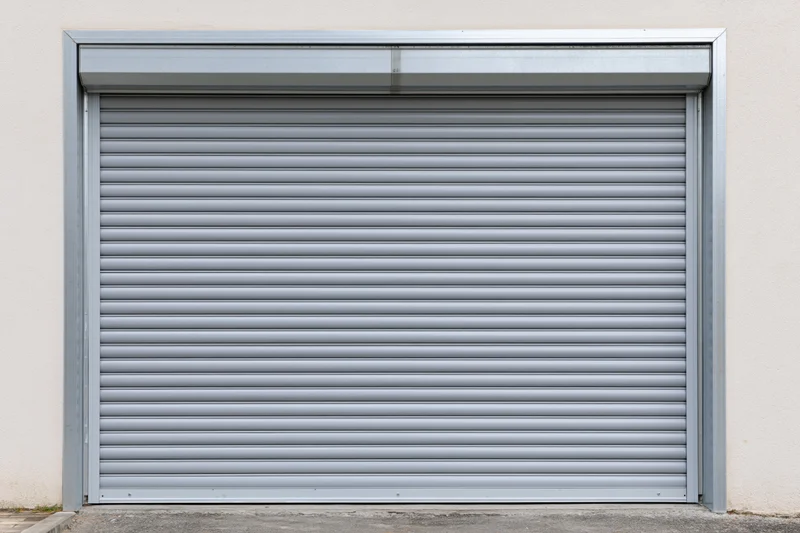 Closed gray metal roller shutter door on a plain building exterior