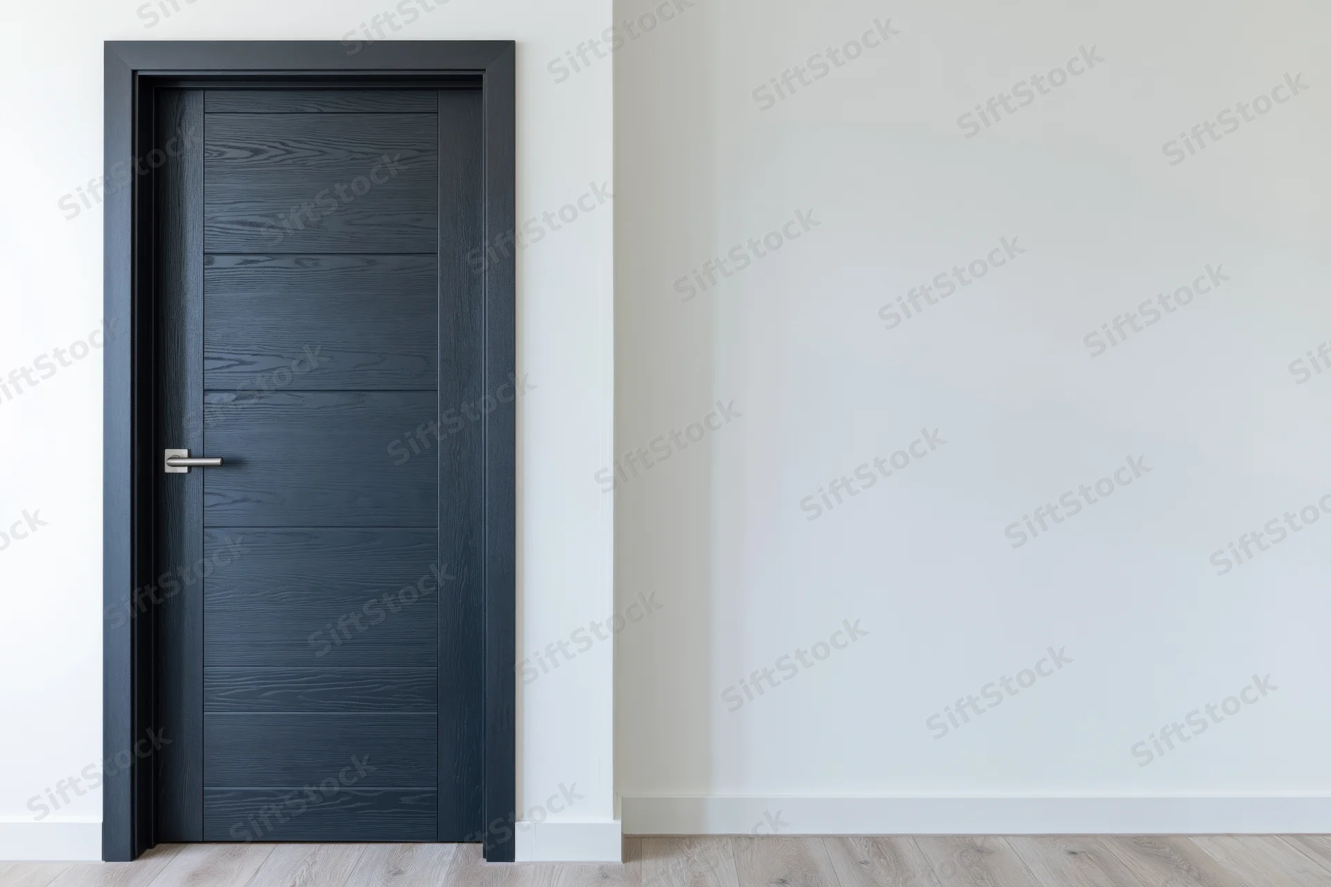 Dark charcoal grey wooden interior door with horizontal panels and metal handle in a minimalist hallway with white walls and light wood flooring