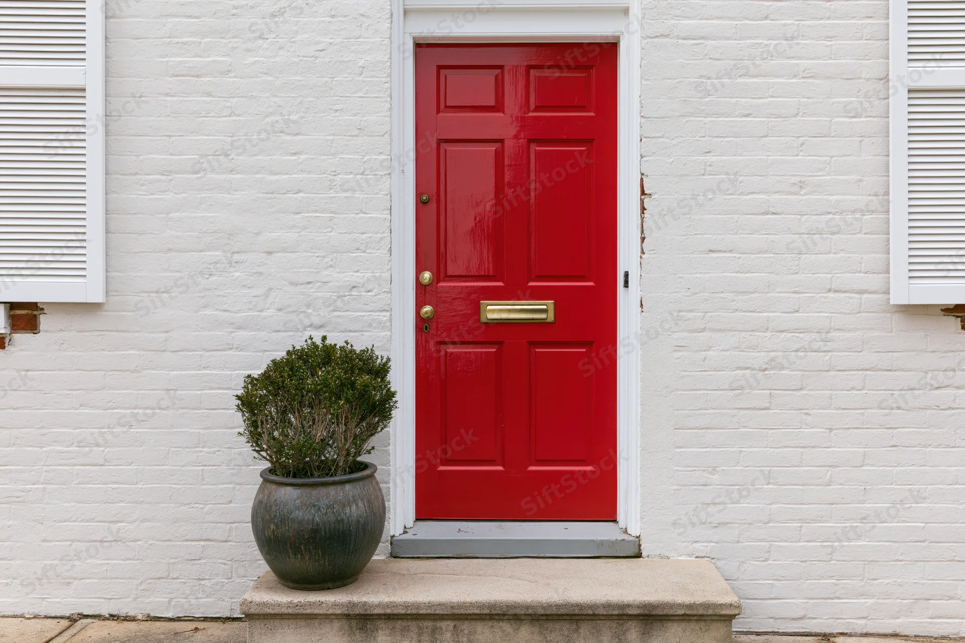 Red six-panel front door with brass hardware on white brick house exterior