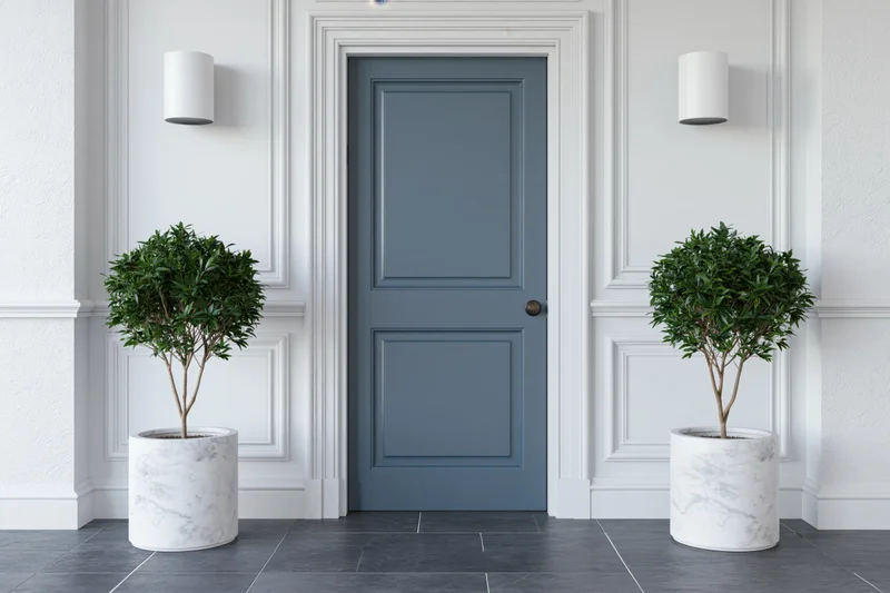 Slate-blue interior door centered between two potted plants in a white paneled entryway