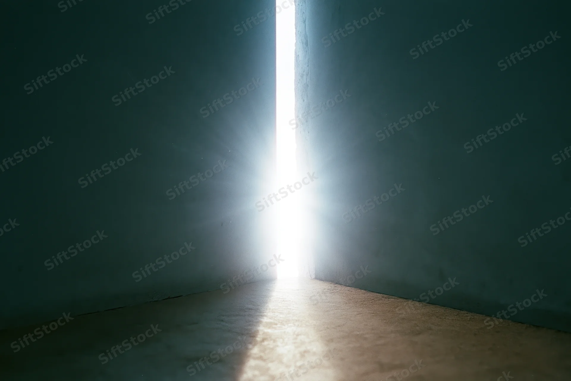 Bright light streaming through a narrow gap between dark concrete walls in a dim interior space