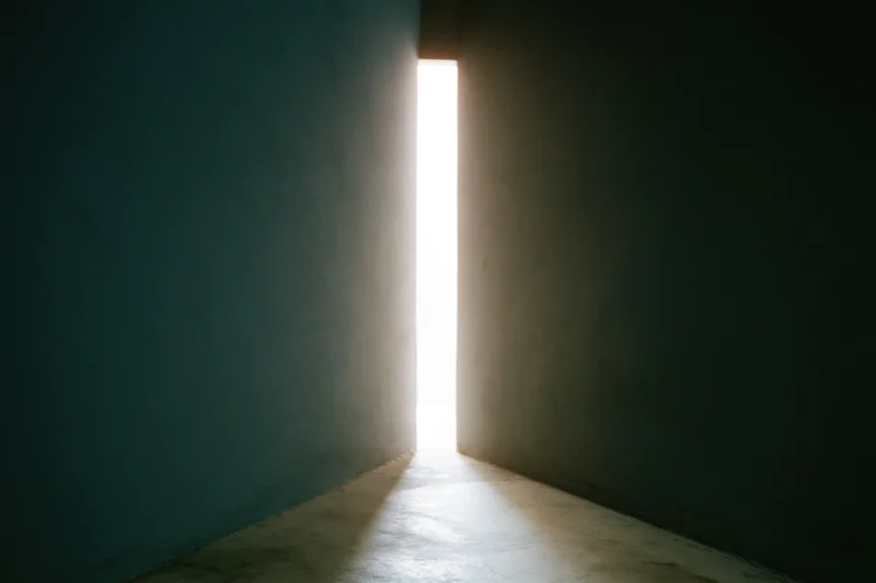 Narrow vertical gap between dark concrete walls letting in bright light